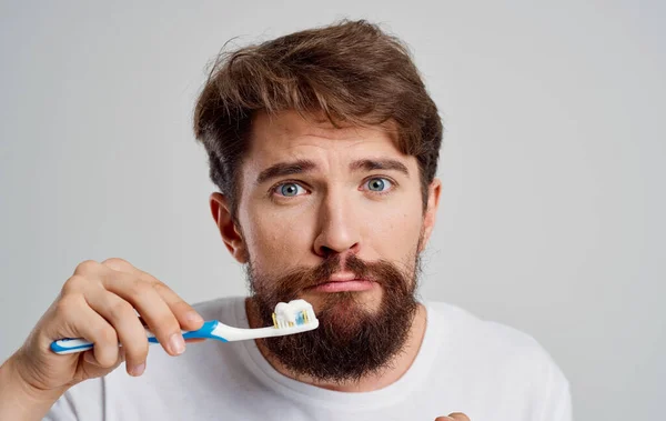 Un hombre con un cepillo de dientes gestos con las manos dolor en la cavidad oral procedimientos matutinos — Foto de Stock