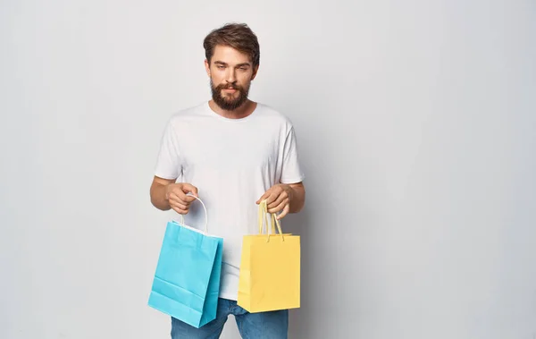 Hombre en camiseta blanca y jeans con paquetes en las manos diversión compras alegría lámina aislada —  Fotos de Stock