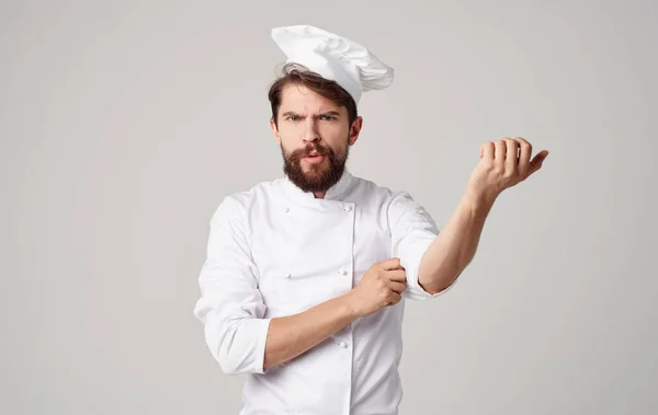 Chef professionista in una tuta leggera gesticolando con le mani su uno sfondo beige — Foto Stock