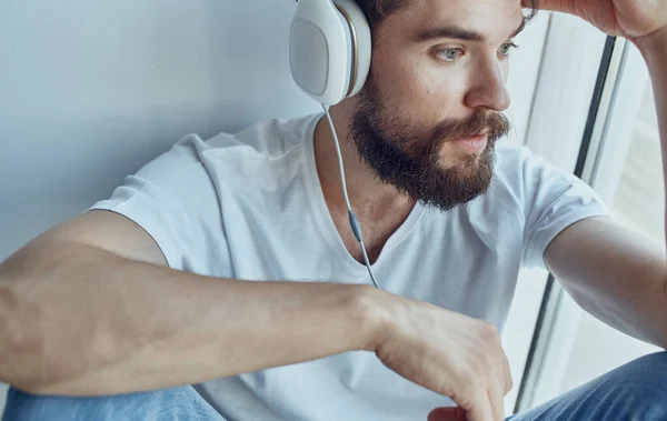 Brodaty mężczyzna w słuchawkach słuchając muzyki przy oknie zabawy — Zdjęcie stockowe