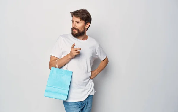 Sokszínű csomagok egy férfi fehér póló bevásárló stúdió kezében — Stock Fotó