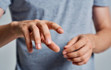 Gri arka planda tişörtlü bir adamın parmağında bakteriyel alçı var.