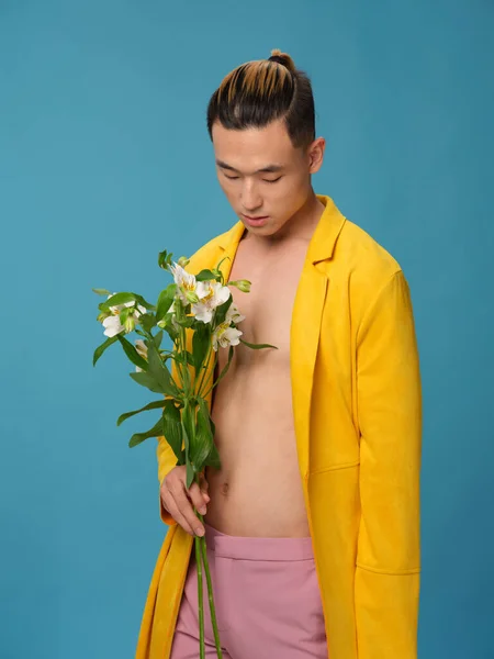 Homem asiático em um fundo azul com um buquê de flores brancas olhando para baixo — Fotografia de Stock