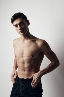 Pantolonlu kaslı adam çıplak gövdesini gri arka plan üzerinde kırpmış.