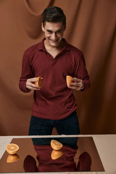 Man met sinaasappels in zijn handen rood shirt glimlach spiegel op de tafel — Stockfoto