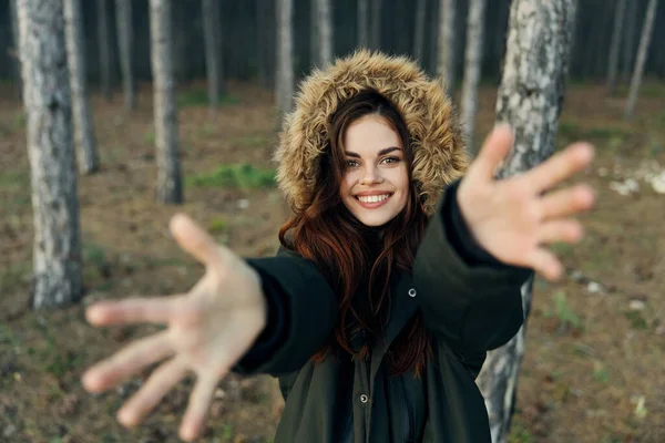 Mujer alegre en el bosque sostiene sus manos delante de ella viajando sobre un fondo de madera —  Fotos de Stock