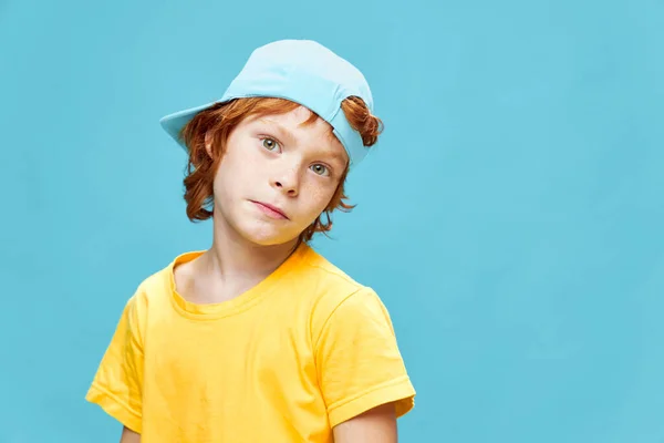 Roodharige jongen met een blauwe pet op zijn hoofd geel t-shirt modieuze kleding studio — Stockfoto