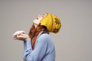 Elinde peçete olan bir kadın enfeksiyon kapmış. Burnu akıyor. Sağlık sorunları var.