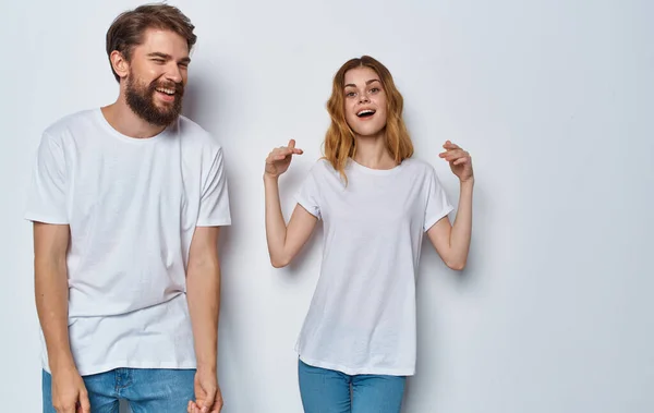 Ευτυχισμένος άντρας και γυναίκα με τζιν και μπλουζάκια σε ανοιχτόχρωμο φόντο — Φωτογραφία Αρχείου