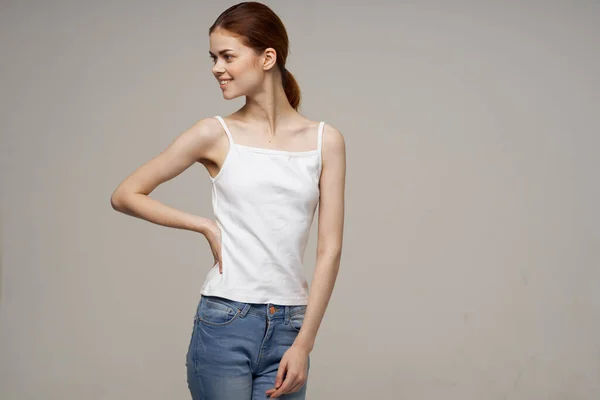 Красива руда жінка в білій футболці та джинсах посміхається студійний стиль життя — стокове фото