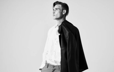 Gri arka plan manzaralı, elinde ceketi olan bir adam.