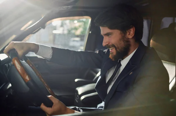 Cheerful man in a suit driving a car Rich man passenger emotions