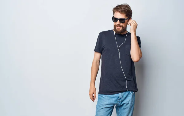 Mężczyzna w okularach słucha muzyki ze słuchawkami elegancki styl studio styl życia — Zdjęcie stockowe