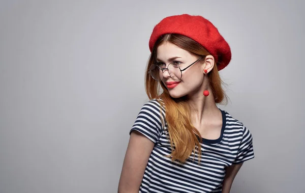 Красива леді в футболці жестикулює руками окуляри червоний капелюх модель — стокове фото
