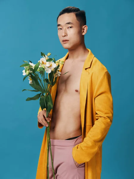 裸の胴を持つハンサムな男と彼の手に花の花束と黄色のコート — ストック写真