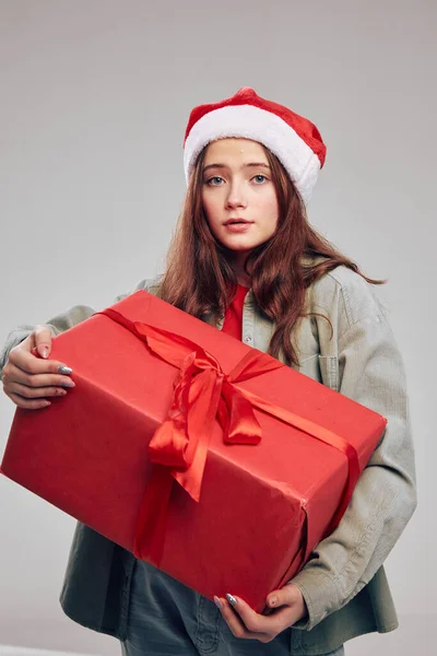 Hediye kutusu olan ve Noel Baba şapkası takan bir kız. Yakından çekilmiş bir portre. — Stok fotoğraf