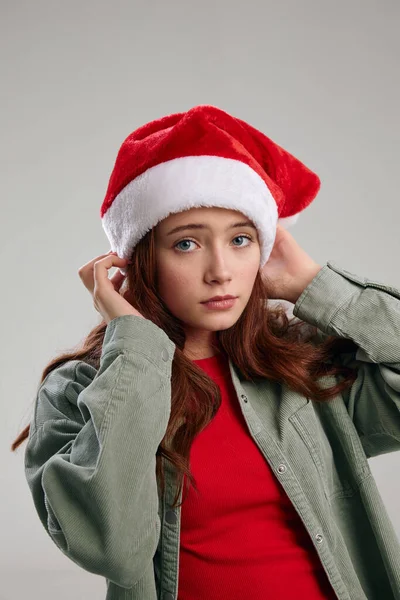 Щаслива маленька дівчинка в червоному капелюсі Санта Клауса на сірому фоні, обрізаному — стокове фото
