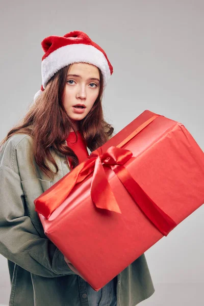 Bir hediye kutusu ve büyük bir Noel yayı ile şenlikli şapkalı güzel küçük kız. — Stok fotoğraf
