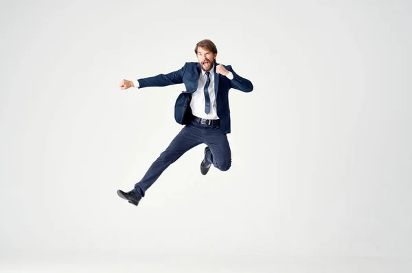 Homem de negócios energético em um terno azul salta em um fundo leve emoções alegria sucesso — Fotografia de Stock