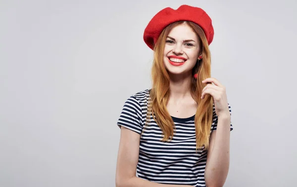 빨간 모자를 쓴 행복 한 모델 그리고 가벼운 배경 감정 초상화에 줄무늬 티셔츠를 입은 모습 — 스톡 사진