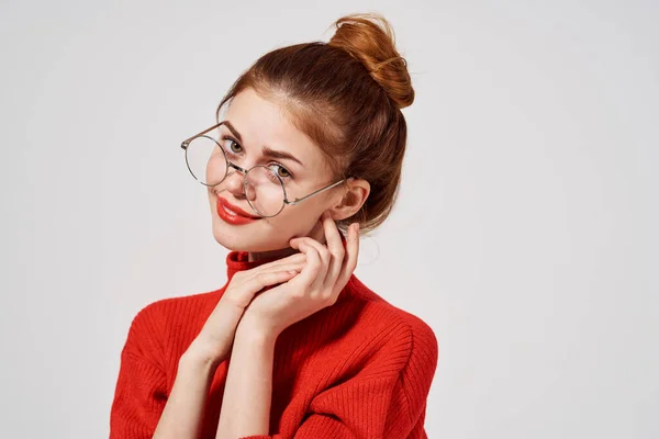 Porträtt av en vacker kvinna med glasögon och en röd tröja makeup ljus bakgrund — Stockfoto