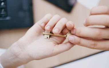 Masadaki ofisteki bir kadının elindeki anahtar.