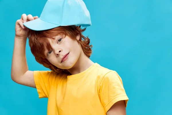 Roodharige jongen draagt een pet op zijn hoofd blauwe achtergrond — Stockfoto