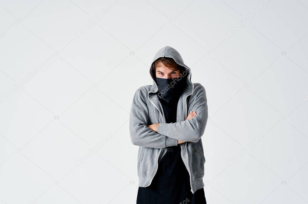 male hacker in a gray sweater stealing black mask on his face