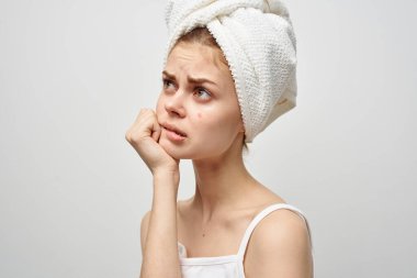 Gözlüklü kadın yüzünde kırmızı bir sivilceye parmak gösteriyor. Sağlık sorunları var.