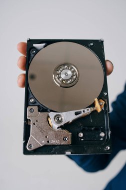 Hard disk, gri bir arka planda bir adamın elinde parçalara ayrıldı.