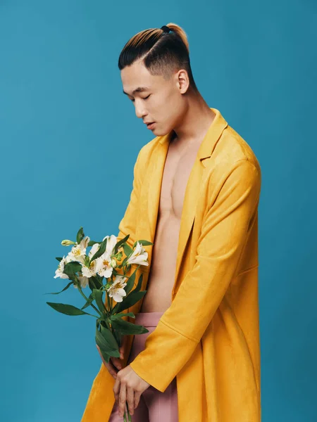 Oldalnézet egy úriember sárga kabátban egy csokor fehér virág a kék háttér — Stock Fotó