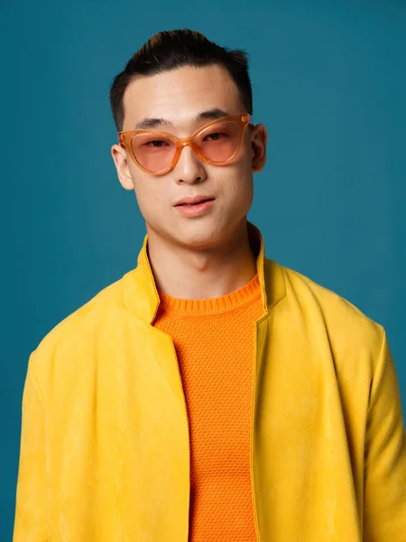 Πορτρέτο ενός Ασιάτη που φοράει γυαλιά πορτοκαλί t-shirt κίτρινο σακάκι μπλε φόντο — Φωτογραφία Αρχείου