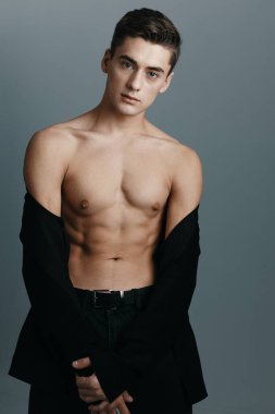 Çıplak gövdeli ve pantolonlu bir adam düğmesiz bir ceket mankendir.