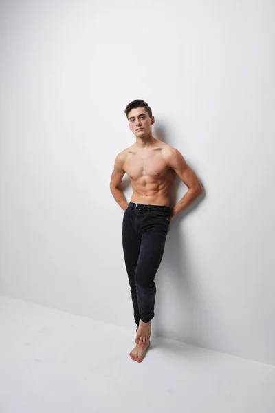 A man with a naked torso sports figure pants light background room — Stock Photo, Image