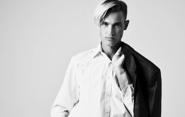 Gri arka plan manzaralı, elinde ceketi olan bir adam.