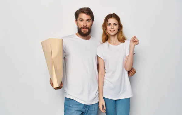 Giovane famiglia in bianco t-shirt pacchetto con generi alimentari viaggio di shopping isolare sfondo — Foto Stock