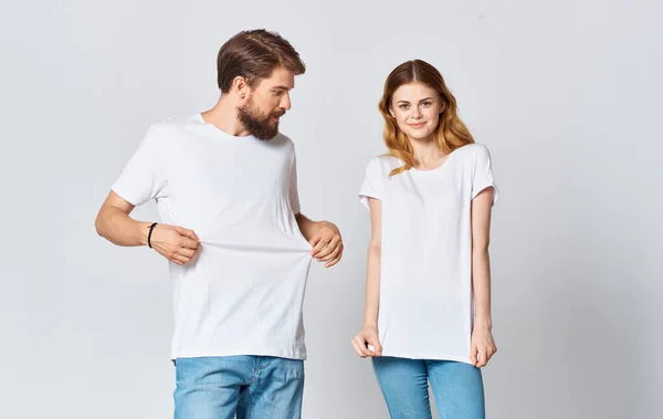 Ritratto di un uomo e una donna in magliette identiche jeans adolescenti sfondo chiaro — Foto Stock