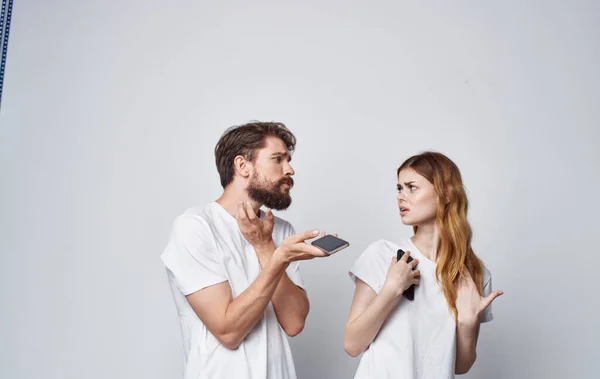 Άνδρας και γυναίκα σε λευκό t-shirts με τηλέφωνα στα χέρια ρομαντική τεχνολογία επικοινωνίας — Φωτογραφία Αρχείου