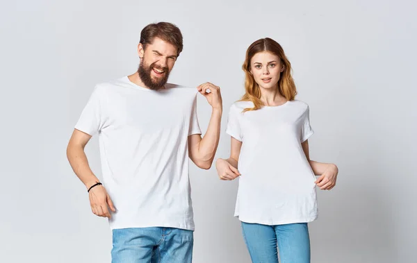 Ritratto di un uomo e una donna in magliette identiche jeans adolescenti sfondo chiaro — Foto Stock
