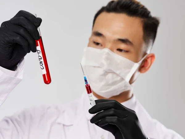 Uomo di aspetto asiatico Tubo di prova con guanti di sangue nero laboratorio di diagnostica — Foto Stock