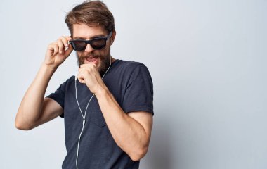 Güneş gözlüklü bir adam hayali bir mikrofon müzik kulaklığına şarkı söylüyor.