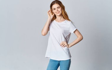 Beyaz tişörtlü güzel bir kadın ve gri arka planda kot pantolon. Boşluğu kopyala.