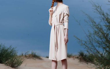 Kadın dışarıda kum yeşili çalıların arasında.