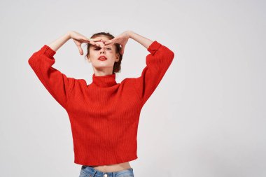 Kırmızı kazaklı güzel bir kadının portresi. Elleri yüzünün yanında.