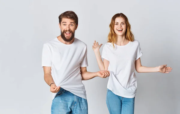 Homem emocional em uma camiseta e uma mulher de jeans em um fundo leve tecido roupas estilo de moda — Fotografia de Stock