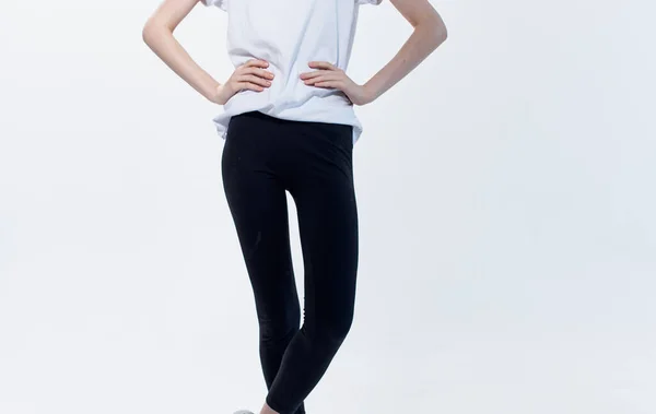 A woman in a white T-shirt and black leggings on a light background gestures with her hands cropped view — Stock Photo, Image