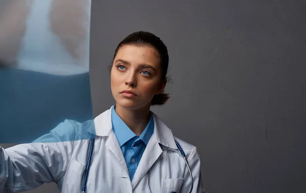 Lékař v lékařských šatech s rentgenem na šedém pozadí výzkumu v laboratoři — Stock fotografie