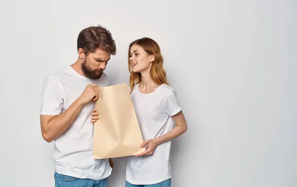 Família jovem em t-shirts brancas pacote com compras compras viagem isolar fundo — Fotografia de Stock