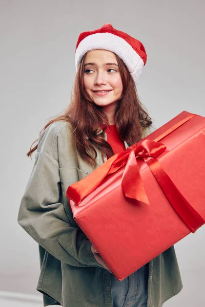 Dziewczyna w kapeluszu z dużym świątecznym polu w jej rękach na szarym tle — Zdjęcie stockowe