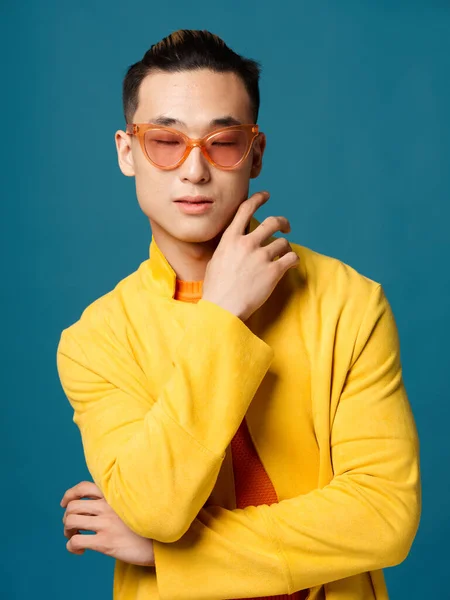 Chico de moda en gafas sobre un fondo azul y una chaqueta amarilla recortada vista del modelo — Foto de Stock